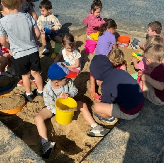 Kids digging with buckets in sand.