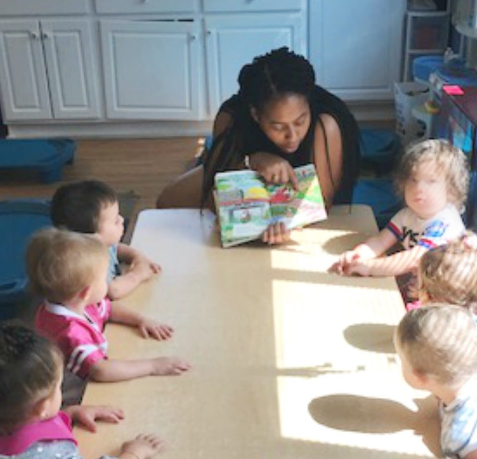 Educator engaging toddlers with a book.